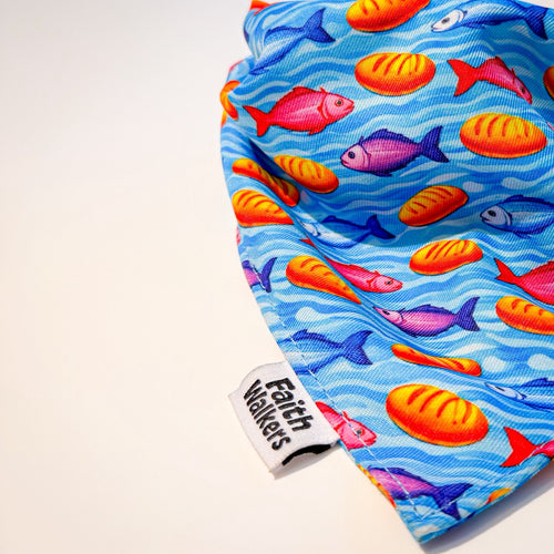 Close-up of the blue Loaves and Fishes bandana with colorful fish, bread loaves and a Faith Walkers label.