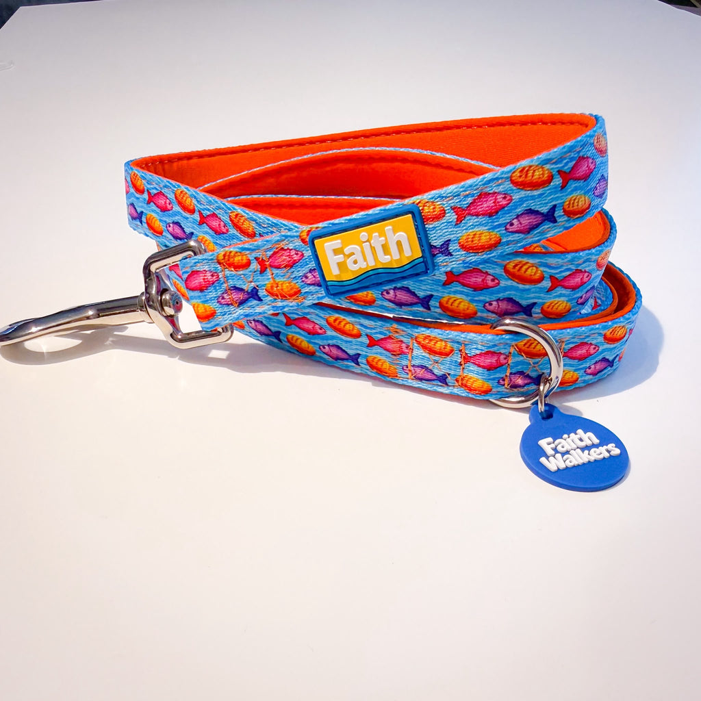 Blue Loaves and Fishes leash with orange lining, a silver clasp, yellow Faith patch and blue Faith Walkers tag.